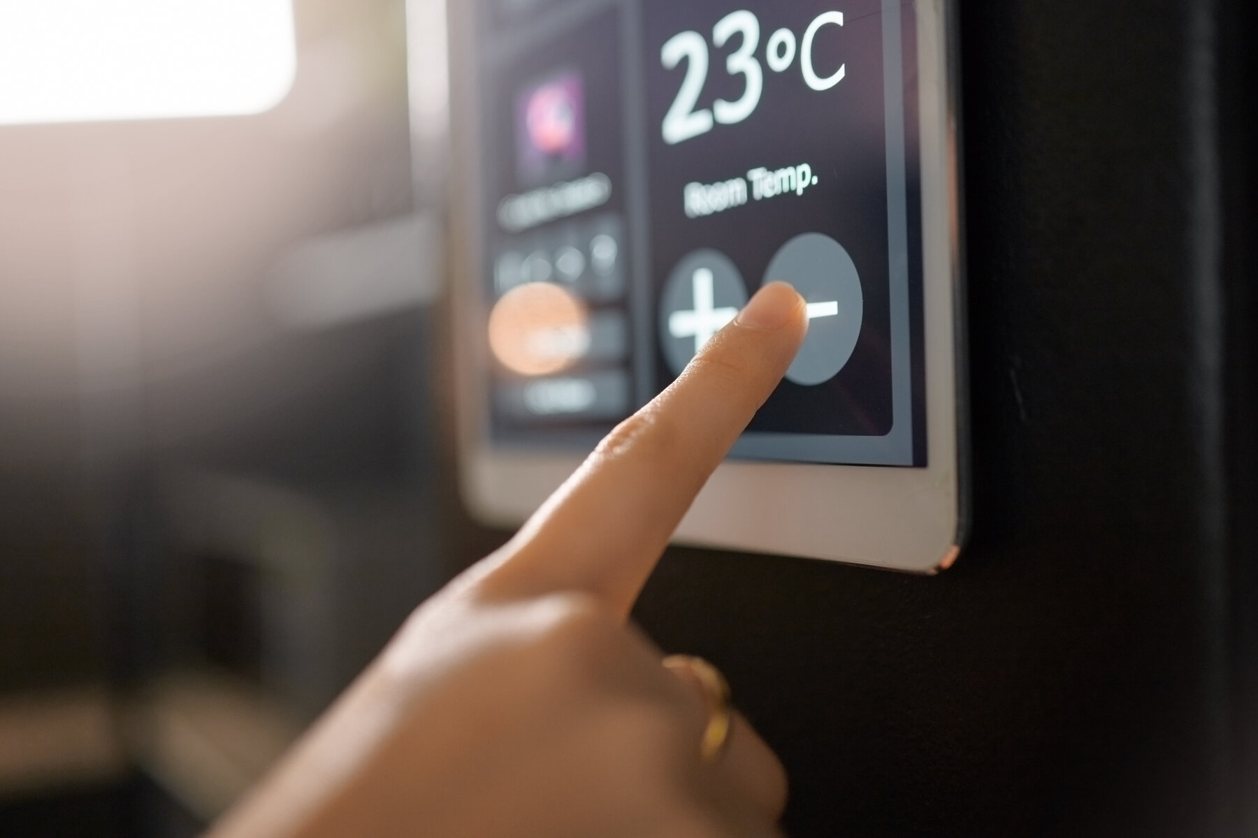 Hand bedient ein Smart Thermostat mit Temperaturanzeige 23 °C